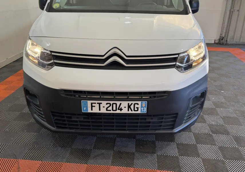 Vue frontale d'un Citroën Berlingo blanc 2020 avec phares allumés et pare-chocs noir mat visible.