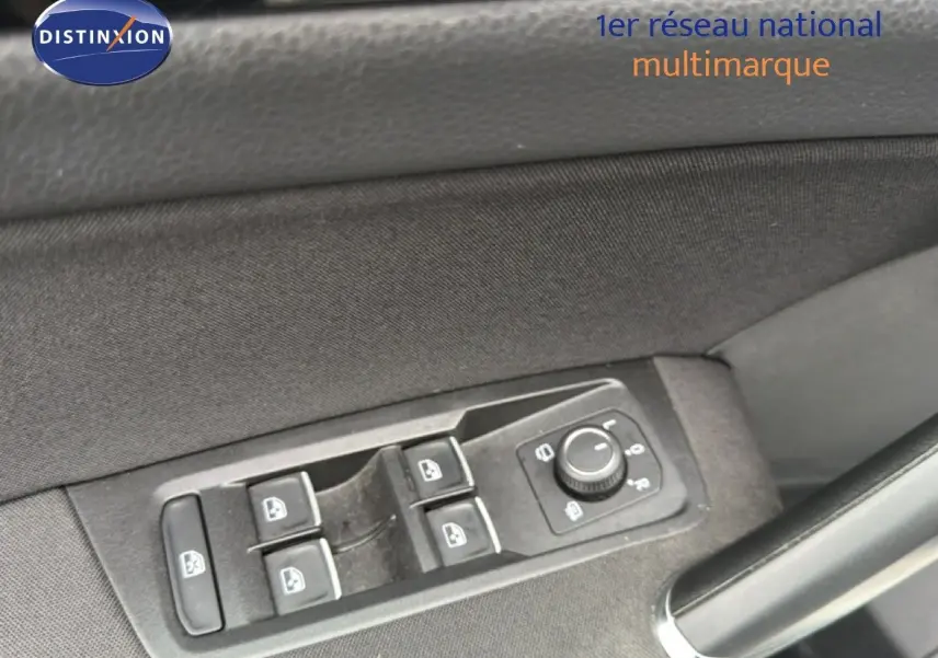 Gros plan sur les commandes des vitres électriques et réglage des rétroviseurs côté conducteur d’un Volkswagen Touran blanc.