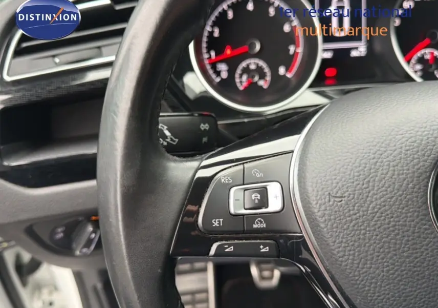 Gros plan sur le volant noir du Volkswagen Touran blanc 2018, montrant les commandes de régulateur de vitesse.