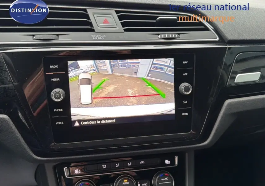 Écran central affichant la caméra de recul du Volkswagen Touran blanc, vue intérieure du tableau de bord.