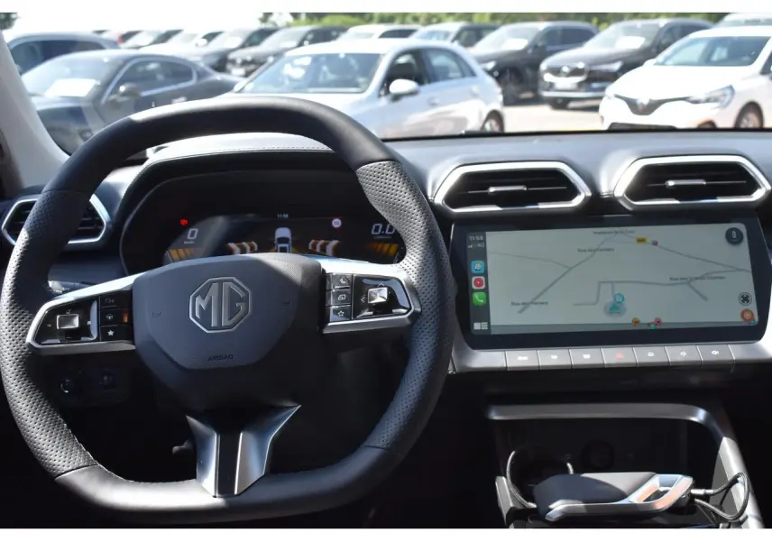 Vue intérieure centrée sur le volant MG et l’écran tactile du tableau de bord du MG ZS blanc 2026 hybride.