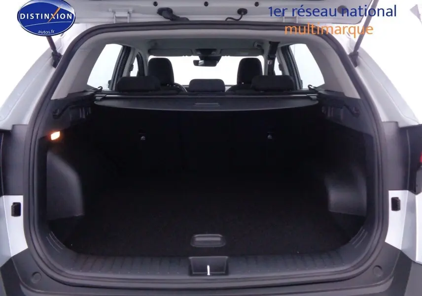 Coffre ouvert vu de l'arrière d'un Kia Sportage gris acier métal, montrant l'espace de chargement vide.