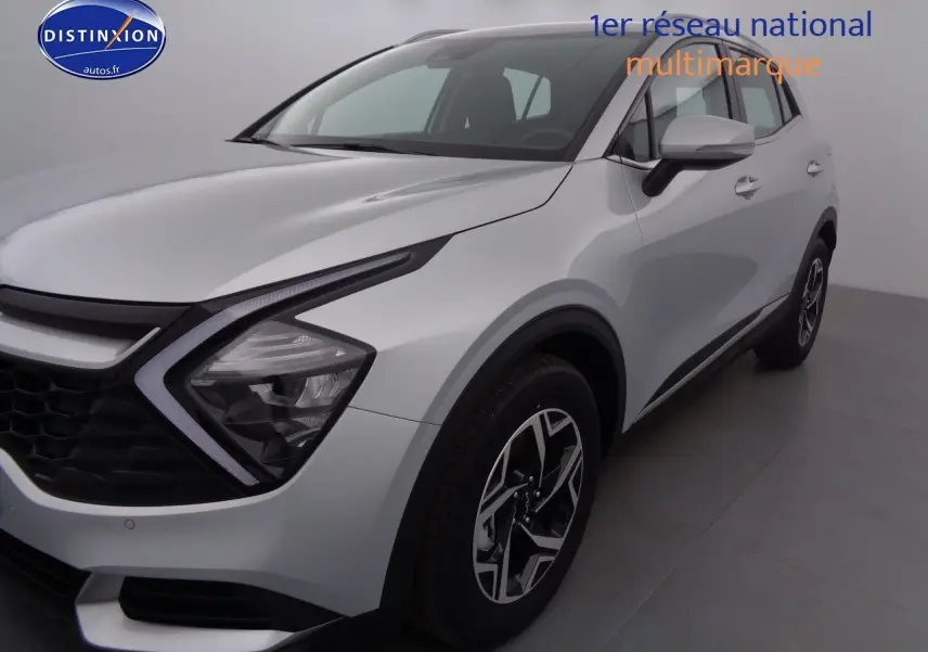 KIA SPORTAGE gris acier métal vu de 3/4 avant droit, mettant en valeur ses phares LED et jantes bicolores.