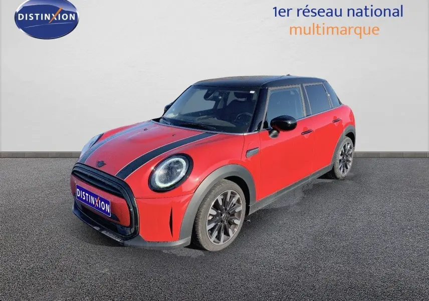 Vue 3/4 avant droite d'une MINI 1.5 136CH rouge chili avec toit noir et bandes noires sur le capot.