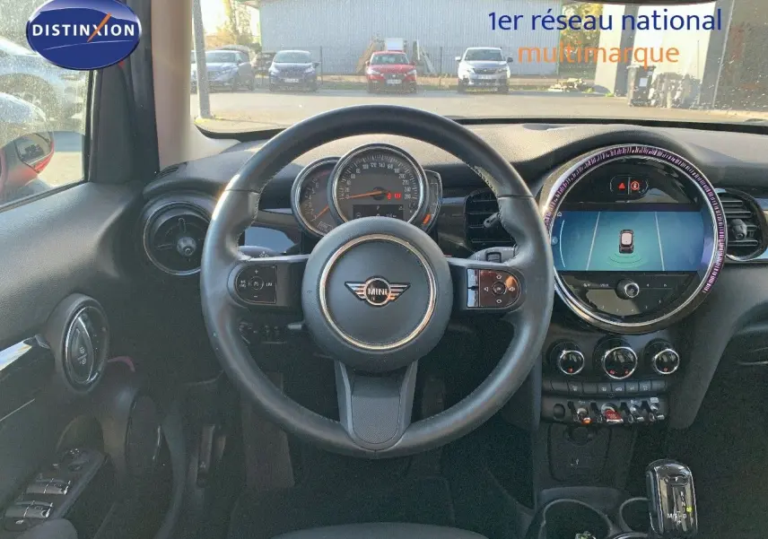Vue intérieure centrée sur le volant et le tableau de bord d'une MINI rouge chili de 2023 avec écran central digital.