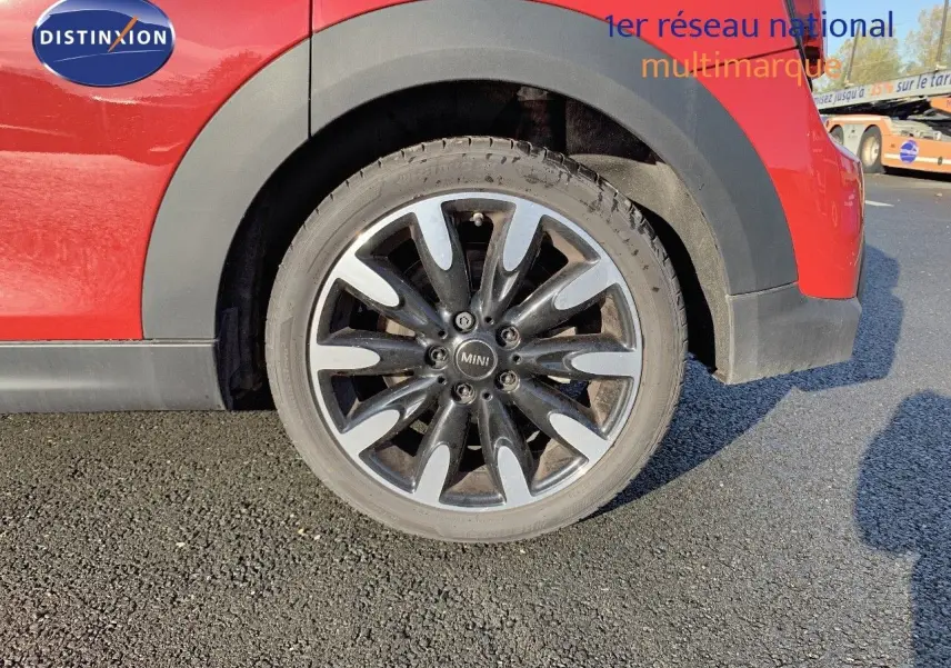 Gros plan sur la roue arrière droite d'une MINI rouge chili avec jante alliage noire et argentée.