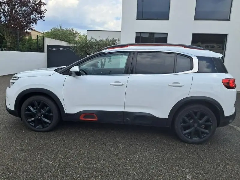Profil côté gauche d'un Citroën C5 Aircross blanc 2019 avec jantes noires et inserts rouges sur les bas de caisse.