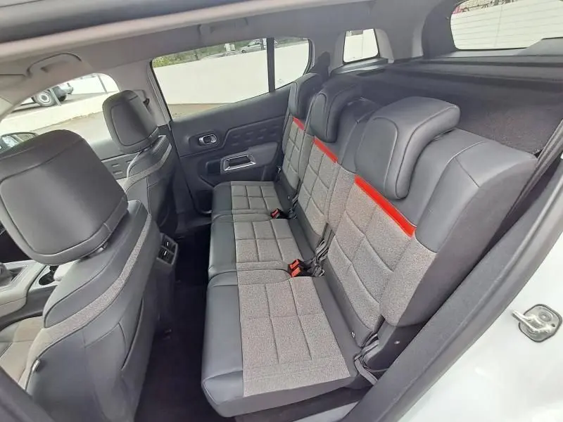 Vue intérieure arrière droite du Citroën C5 Aircross blanc 2019, sièges tissu gris avec détails noirs et bande rouge.