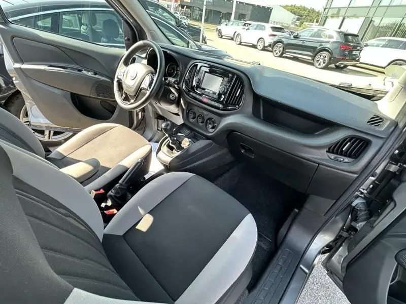 Intérieur du Fiat Doblo Cargo 2021 en gris foncé, vue côté conducteur montrant tableau de bord et sièges tissu bicolore.