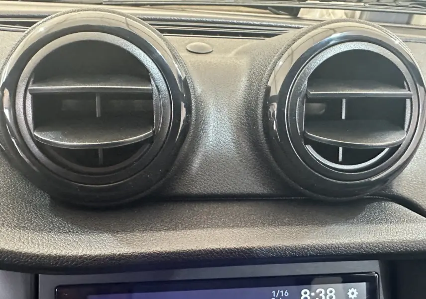 Vue rapprochée des aérateurs ronds noirs du tableau de bord de l'AIXAM AMBITION 0.5 CITY SPORT rouge, année 2026.