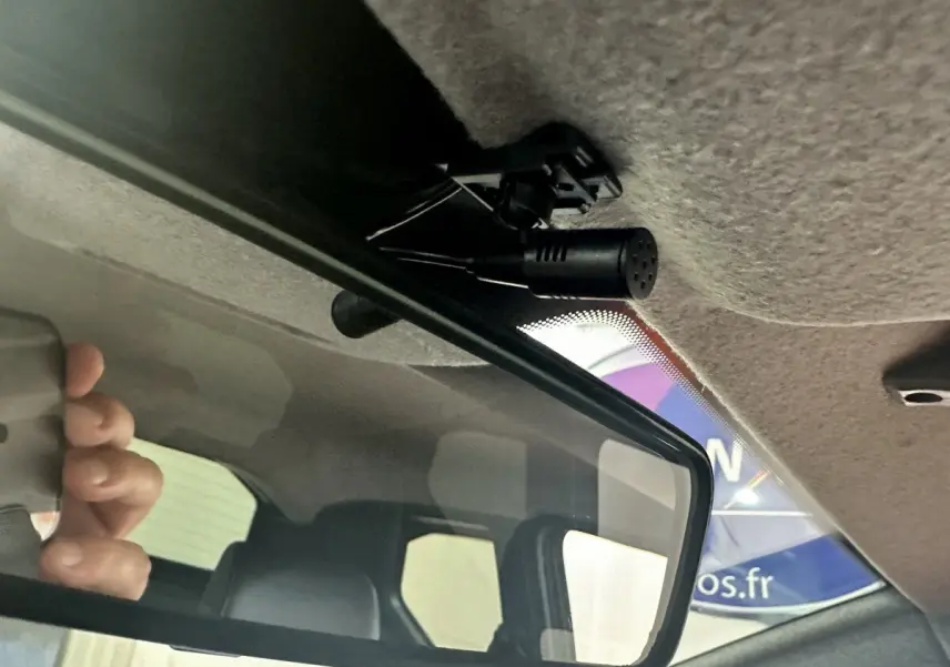 Vue intérieure du rétroviseur central d'une Aixam Ambition 0.5 City Sport rouge, avec micro fixé au plafond.