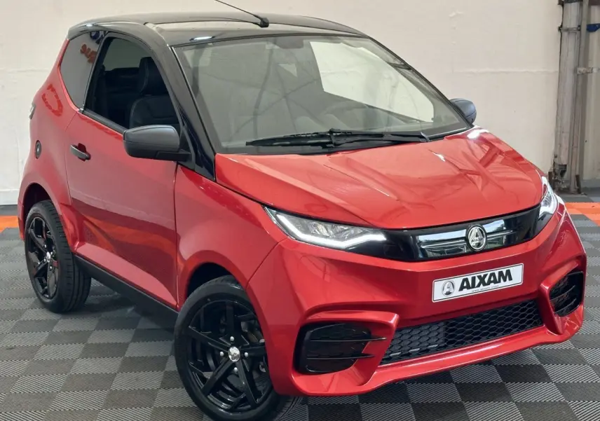 Vue 3/4 avant d'une Aixam Ambition 0.5 City Sport rouge avec toit noir et jantes noires, rétroviseur caméra côté gauche.