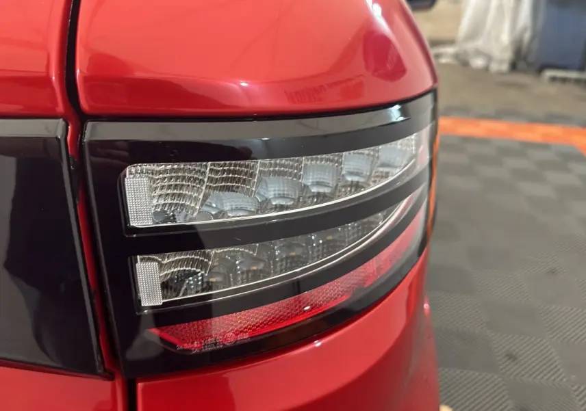 Gros plan sur le feu arrière droit rouge de l'AIXAM AMBITION 0.5 CITY SPORT 2026 avec détails lumineux nets.