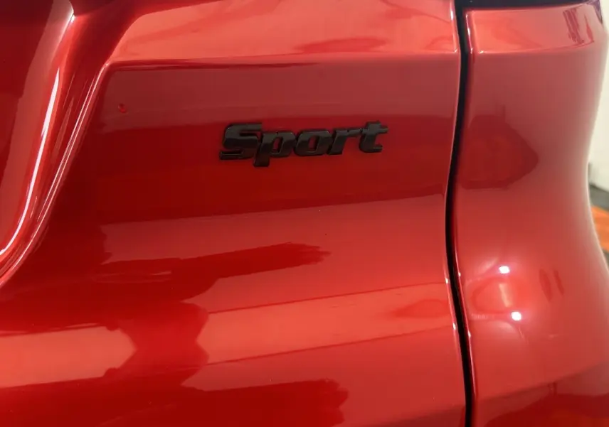 Gros plan sur l'arrière droit rouge de l'AIXAM AMBITION 0.5 CITY SPORT avec logo "Sport" noir brillant.