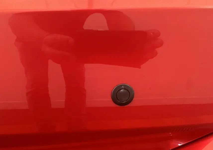 Détail du verrouillage de coffre sur la carrosserie rouge d'une Aixam Ambition 0.5 City Sport, vue rapprochée.