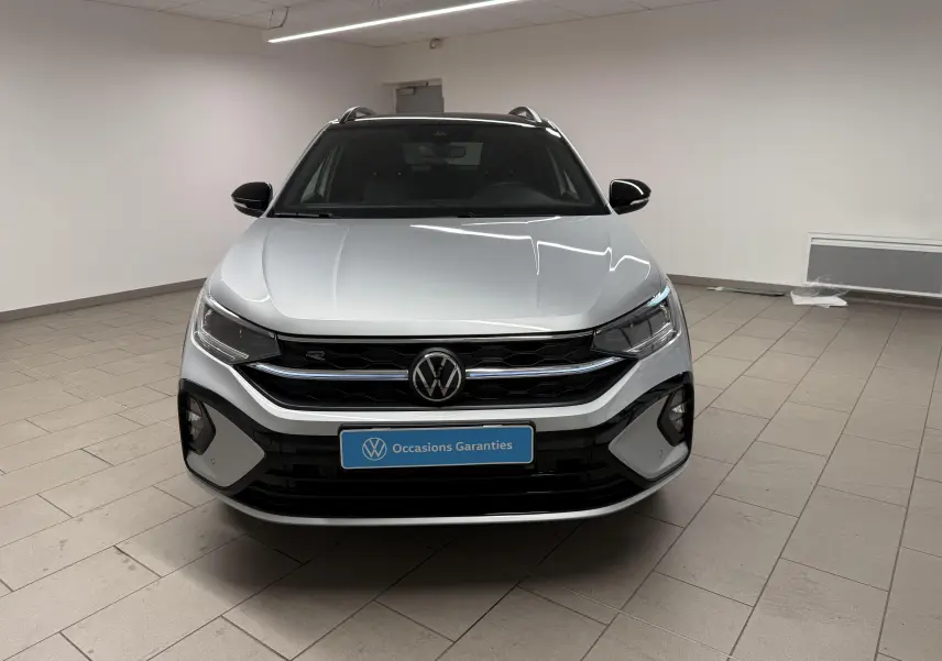 Vue avant d'un Volkswagen Taigo 1.5 TSI 150 DSG7 R-Line édition argent métallisé avec toit noir dans un showroom.