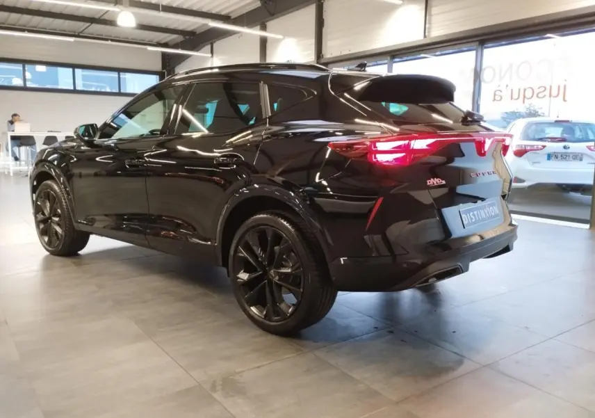 Vue 3/4 arrière droite du CUPRA Formentor noir métal avec jantes alliage noires et feux arrière Tri-LED allumés en showroom.