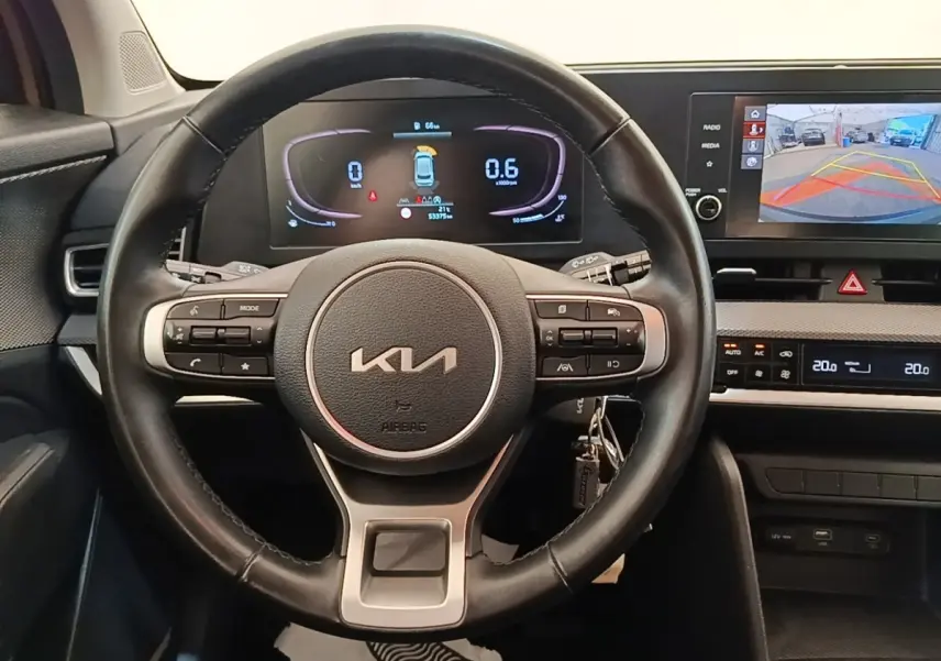 Vue frontale du volant en cuir noir du KIA SPORTAGE 2022 avec tableau de bord numérique et écran tactile de recul.