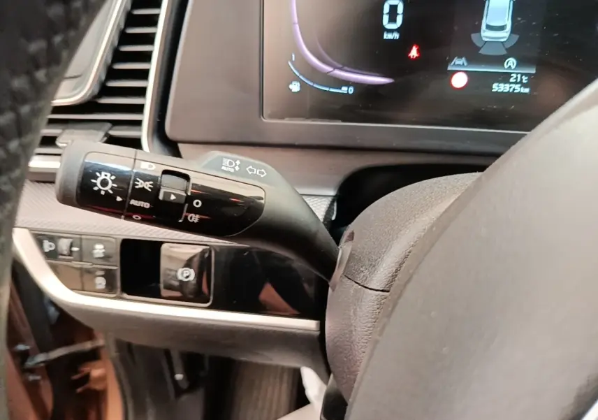 Gros plan sur la manette de commande des phares et clignotants du tableau de bord du KIA Sportage beige 2022.