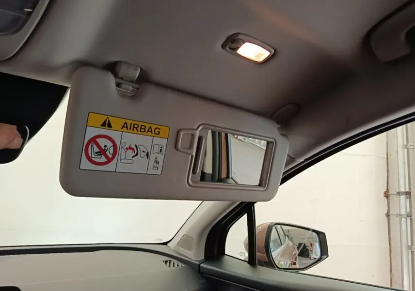 Vue intérieure côté conducteur du Kia Sportage beige 2022, avec pare-soleil rabattable et miroir de courtoisie éclairé.