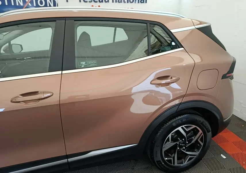 Vue côté droit arrière du KIA SPORTAGE beige 2022 avec jante alliage et poignées de porte assorties.