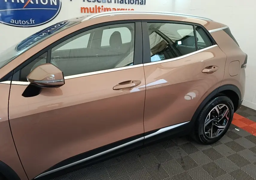 Vue latérale droite du KIA SPORTAGE beige 2022, mettant en valeur les jantes alliage et les rétroviseurs électriques.