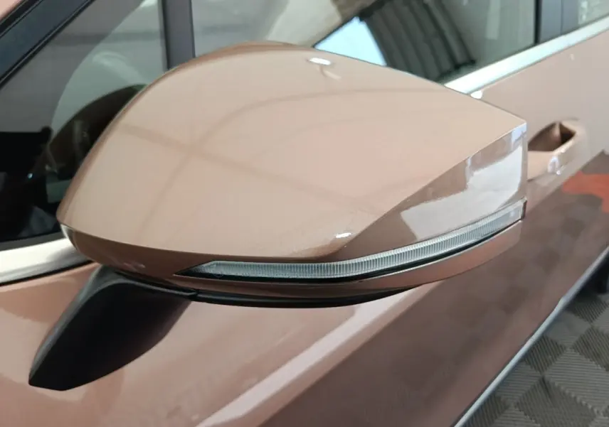 Rétroviseur côté conducteur beige du Kia Sportage 2022 avec clignotant intégré, vu en gros plan depuis l'avant gauche.