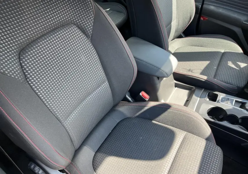 Gros plan sur les sièges avant en tissu noir avec surpiqûres rouges de la Ford Focus SW 2025, intérieur lumineux.