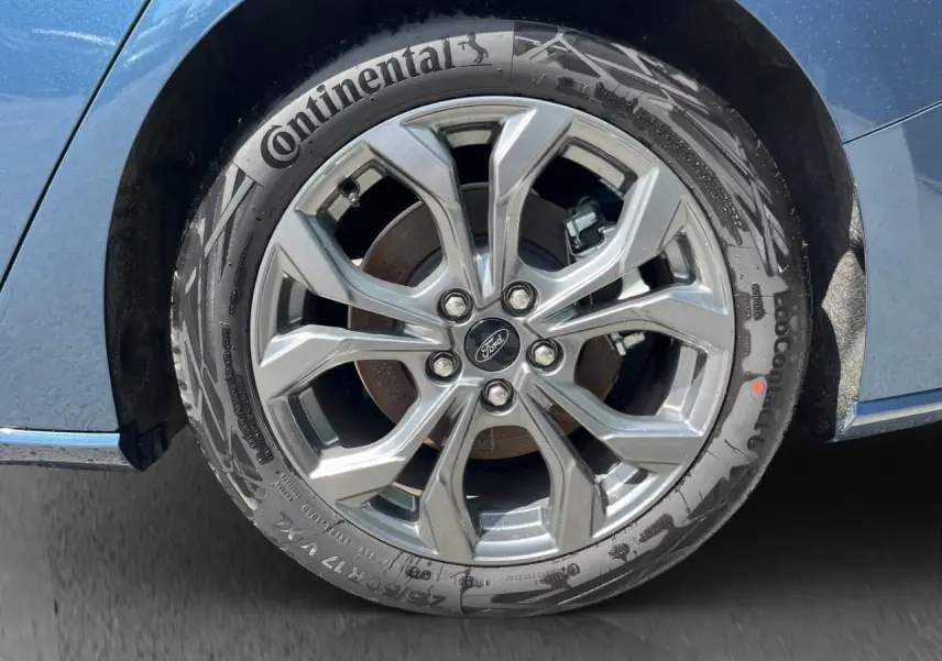 Gros plan sur la roue avant droite d’une Ford Focus SW bleue 2025, jante alliage et pneu Continental visibles.