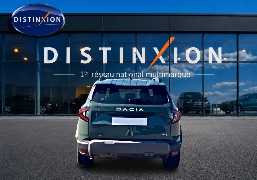 Vue arrière d'un Dacia Duster 1.2 hybrid-g 150 expression 4x4 en kaki lichen, devant une vitrine Distinxion.