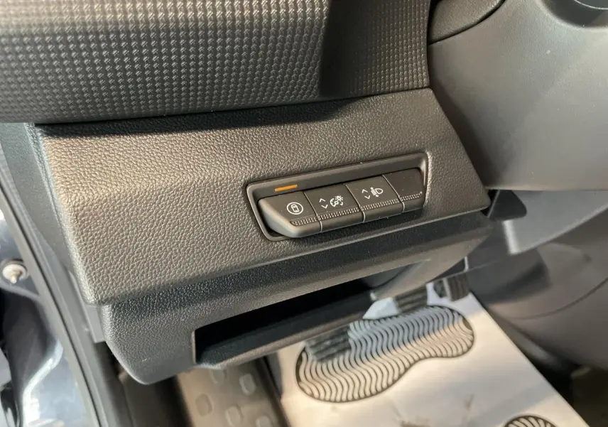 Gros plan sur les commandes sous le tableau de bord côté gauche du Renault Trafic Fourgon gris Comète 2025.