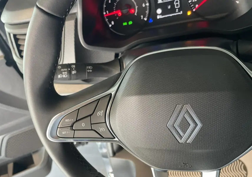 Gros plan sur le volant noir du Renault Trafic Fourgon 2025 avec commandes intégrées et tableau de bord partiellement visible.