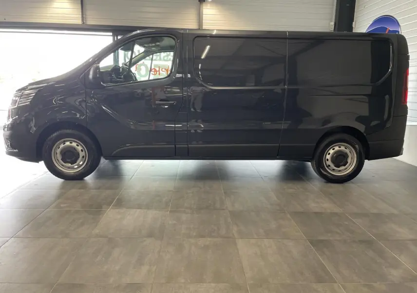 Profil latéral droit d'un Renault Trafic Fourgon gris foncé avec jantes tôles et vitres teintées en showroom.