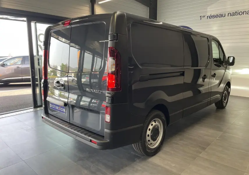 Vue 3/4 arrière droit du Renault Trafic Fourgon L2H1 2025 en gris comète avec portes arrière fermées dans un showroom.