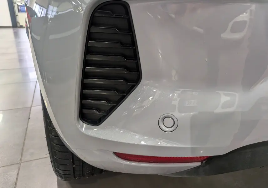 Gros plan sur l'aile arrière gauche gris Rafale d'une Renault Clio V avec capteur de recul et prise d'air noire.