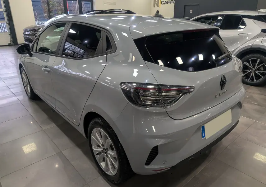 Renault Clio V gris Rafale vue 3/4 arrière droit en intérieur, avec vitres teintées et jantes alliage.
