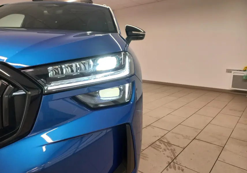 Gros plan sur l’avant droit du Skoda Kodiaq Bleu RS 2024 avec phares LED allumés et calandre noire.