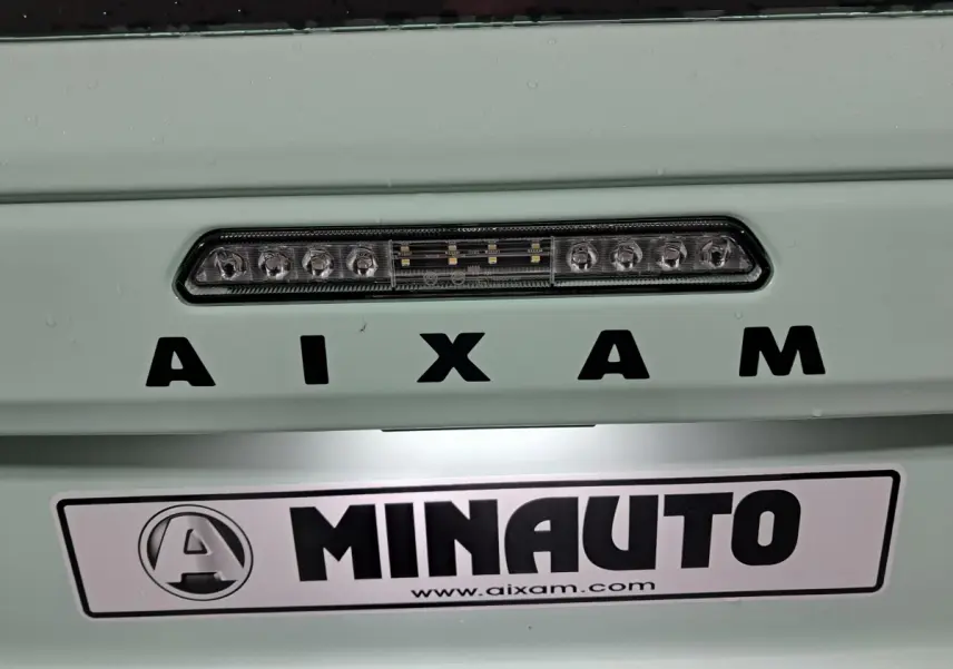 Gros plan sur l’arrière vert clair de l’Aixam MINAUTO avec feu stop LED et logo distinctif visible.