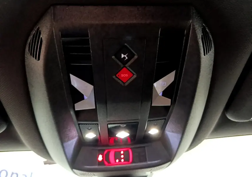 Vue en gros plan du panneau de commandes au plafond du DS7 Crossback gris foncé, avec bouton SOS rouge et éclairage LED blanc.
