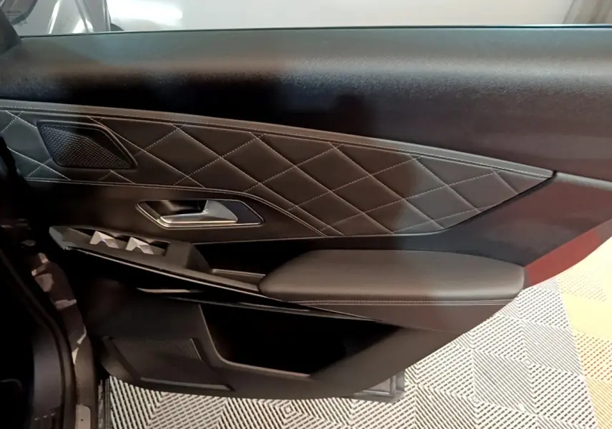 Gros plan sur la porte intérieure côté gauche du DS7 Crossback E-TENSE 4x4 300 RIVOLI avec cuir noir matelassé et commandes électriques.