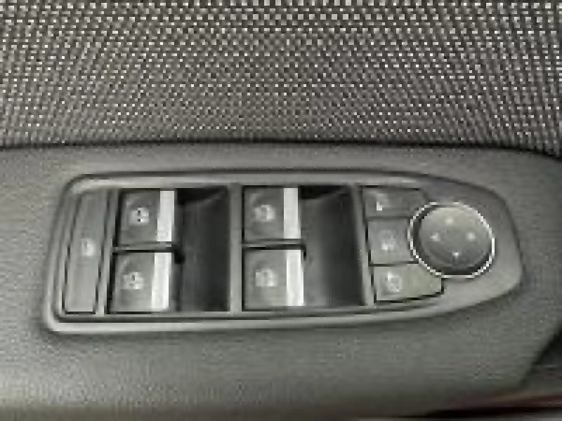 Gros plan sur les commandes de lève-vitres et réglage des rétroviseurs côté conducteur du Renault Captur rouge 2025.