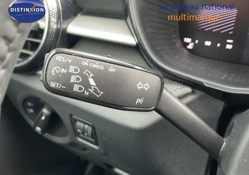 Gros plan sur la commande de régulateur de vitesse à gauche du volant dans l’habitacle gris noir d’une Skoda Fabia 2025.