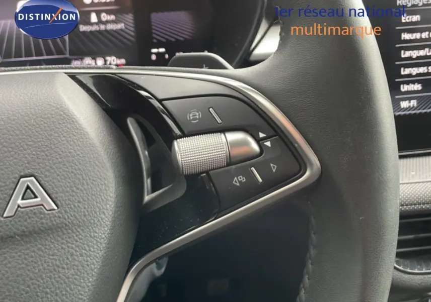 Gros plan sur le volant multifonction noir et gris d'une Skoda Fabia 2025, avec commandes intégrées et tableau de bord numérique en arrière-plan.