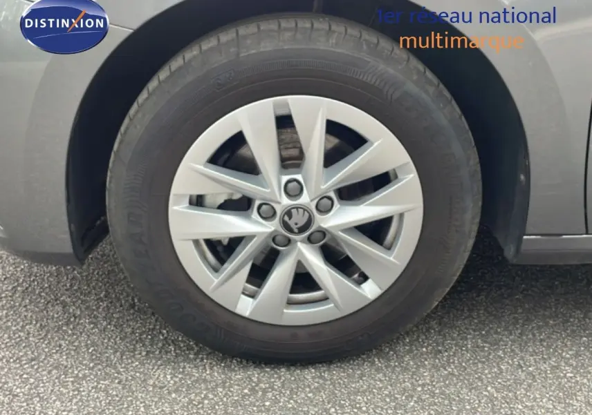 Gros plan sur la roue avant gauche d'une Skoda Fabia gris graphite métal avec jante alliage 15 pouces et logo central visible.