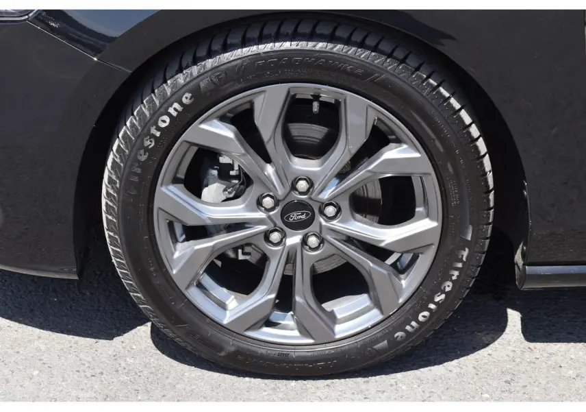 Gros plan sur la roue avant droite de la Ford Focus SW 2025 Agate Black Metallic avec jante alliage et pneu Firestone.