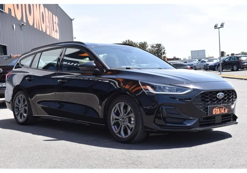Ford Focus SW 1.5 EcoBlue 115 ST LINE X noir métallisé vue 3/4 avant droit, calandre hexagonale et jantes alliage visibles.