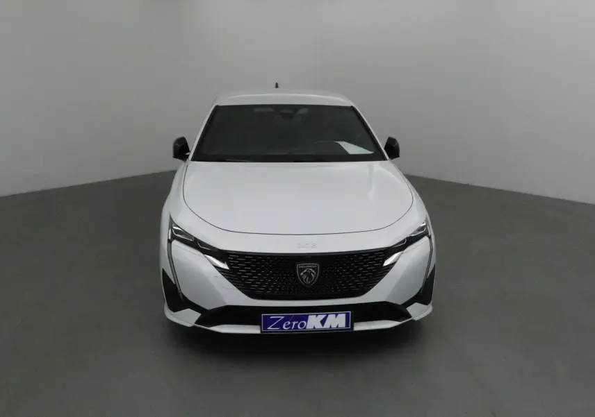 Vue frontale d'une Peugeot 308 blanche Okenite 2025 avec calandre noire et logo lion central bien visible.