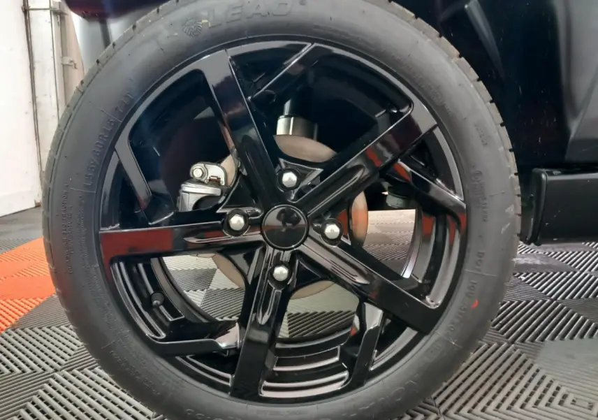 Gros plan sur la roue avant droite avec jante noire brillante du véhicule bleu Aixam MEGA E-Scouty Evo 2026.