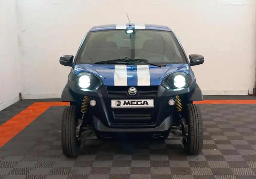 Vue avant d'une Aixam Mega E-Scouty Evo 2026 bleue avec bandes blanches, phares allumés et suspension visible.