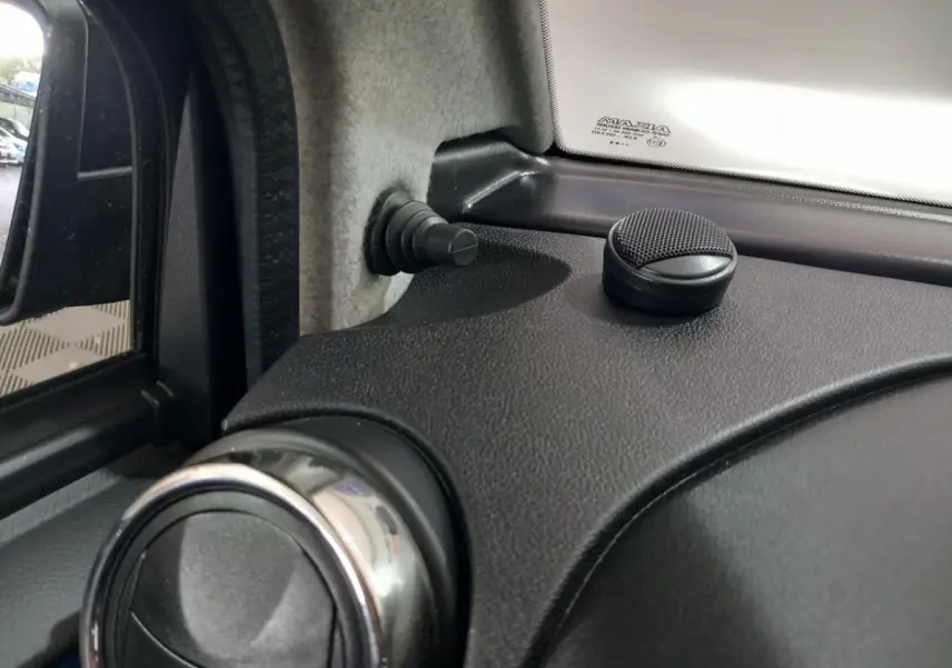 Détail intérieur côté conducteur montrant la commande de ventilation et le bouton de verrouillage sur tableau de bord noir.